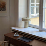 Table lamp in Sage green standing in a window in front of  work desk setup. 