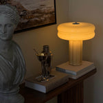 Affiné table lamp with soft amber glow and dimmer, styled on a bookstack on a side table