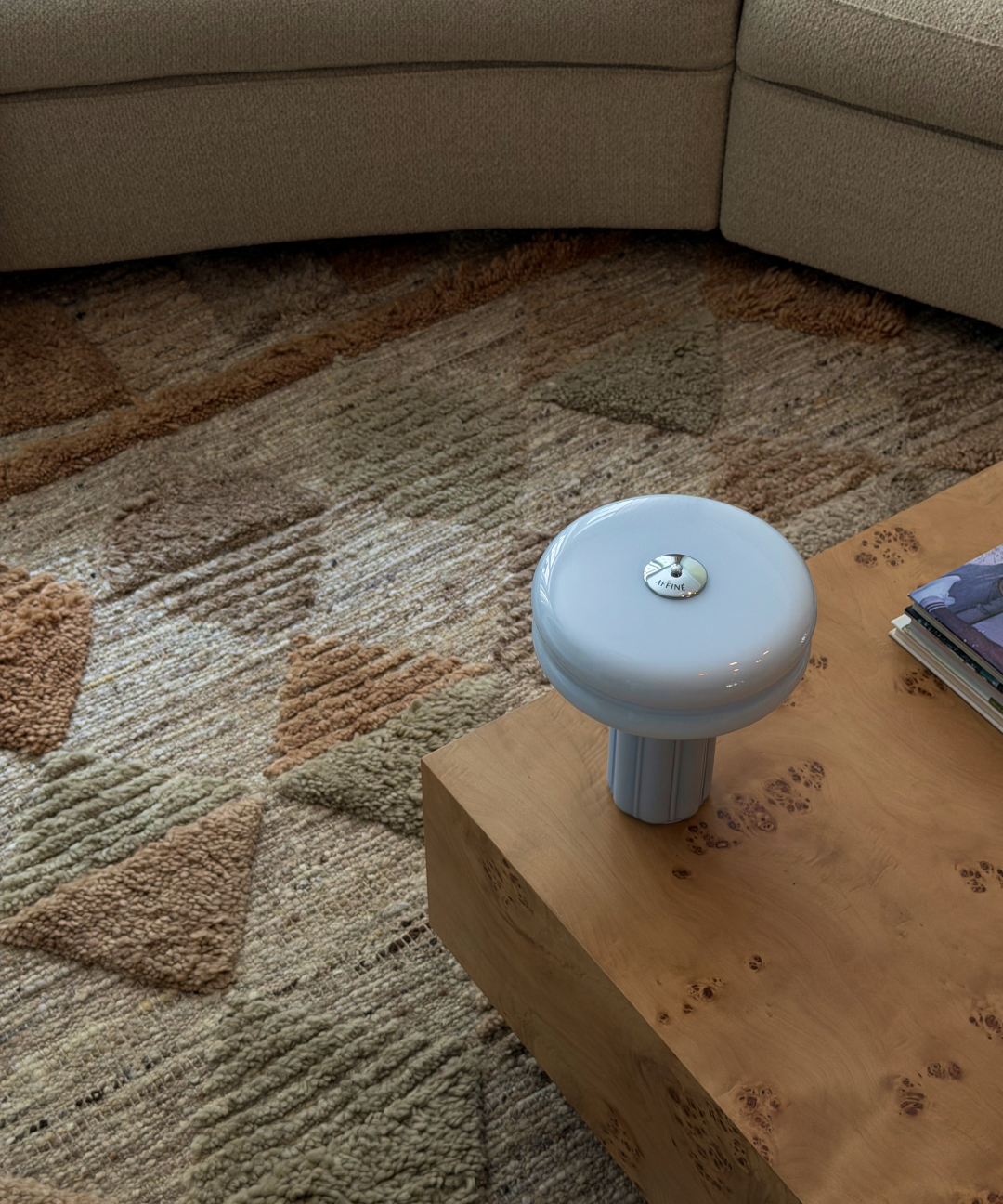 Close-up of the Affiné Portable Lamp in Powder Blue on a table.