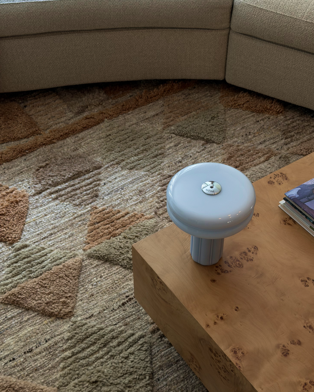 Close-up of the Affiné Portable Lamp in Powder Blue on a table.