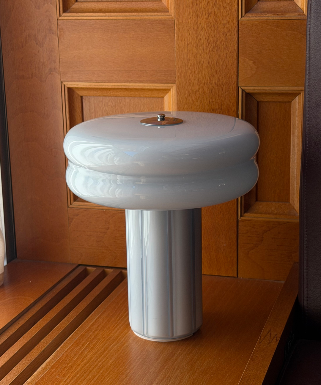 Affiné Portable Lamp in Powder Blue placed by a wooden-framed window.