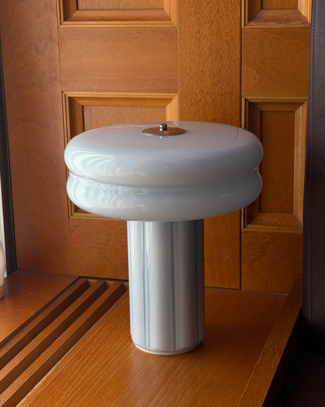 Affiné Portable Lamp in Powder Blue placed by a wooden-framed window.