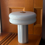 Affiné Portable Lamp in Powder Blue placed by a wooden-framed window.