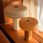 The Affiné Table Lamp in Crème Beige and Portable Lamp in Soft Amber styled together by a wooden-framed window.