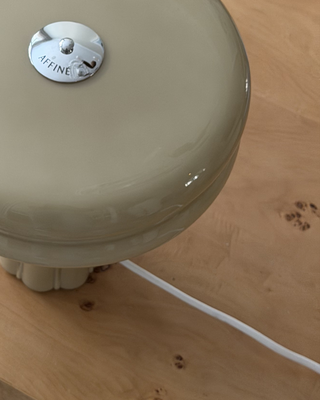 Close-up of the Affiné Table Lamp in Sage Green on a table.
