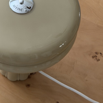 Close-up of the Affiné Table Lamp in Sage Green on a table.