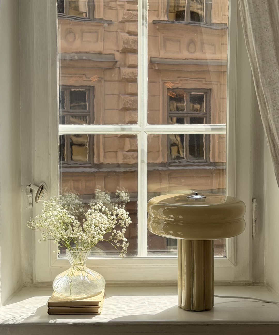Affiné Table Lamp in Sage Green in a wooden-framed window.