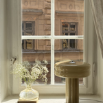 Affiné Table Lamp in Sage Green in a wooden-framed window.