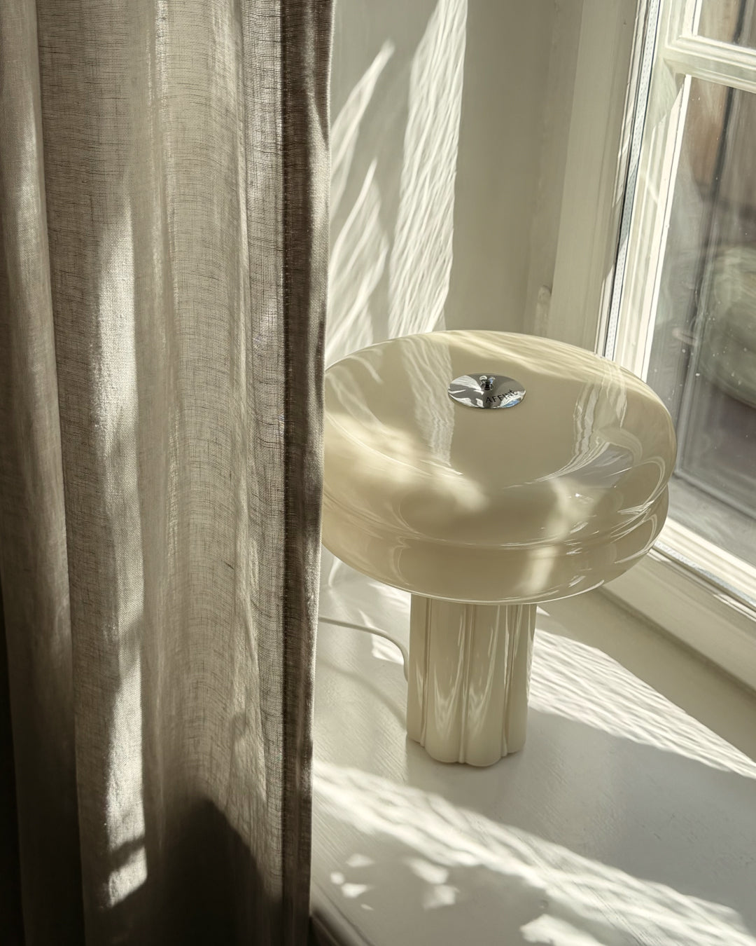 Close-up of the hand-blown glass on the Affiné Table Lamp in Crème Beige.