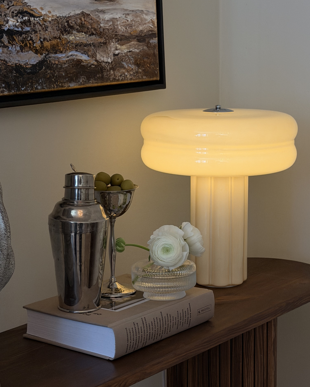 Affiné Table Lamp in Crème Beige styled on a dark wooden sideboard.